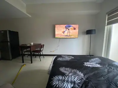 a bedroom with a bed and a tv on the wall at AMAZING VIEWS ACROSS SHANGRILA MALL and NEAR MEGAMALL GREENFIELD DISTRICT in Manila
