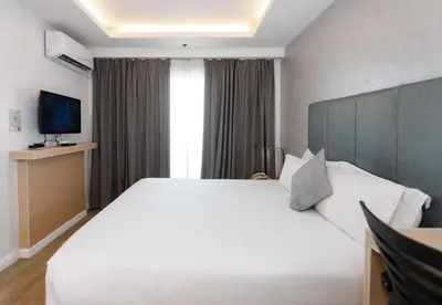 a bedroom with a large white bed and a television at Regency Grand Suites in Manila