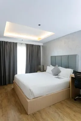 a bedroom with a large white bed and a desk at Regency Grand Suites in Manila