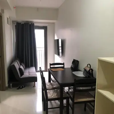 a living room with a dining room table and chairs at Cozy 1 Bedroom with balcony facing pool near MOA,IKEA near in Manila