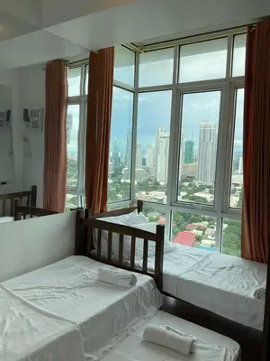 two beds in a room with a large window at Clazzy Home At San Lorenzo in Manila