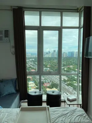a bedroom with a large window with a view of a city at Clazzy Home At San Lorenzo in Manila