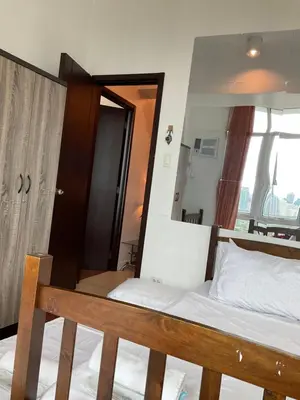 a bedroom with a bed with a wooden frame and a mirror at Clazzy Home At San Lorenzo in Manila