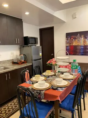a kitchen with a table with chairs and a kitchen with a tableablish at Clazzy Home At San Lorenzo in Manila