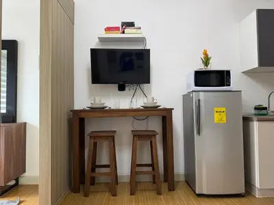 a kitchen with a small table with a refrigerator and stools at Sunshine at Grace nr BGC in Manila