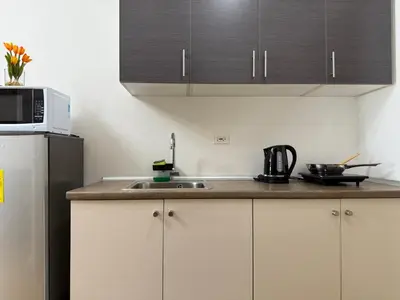 a kitchen with a sink and a refrigerator at Sunshine at Grace nr BGC in Manila