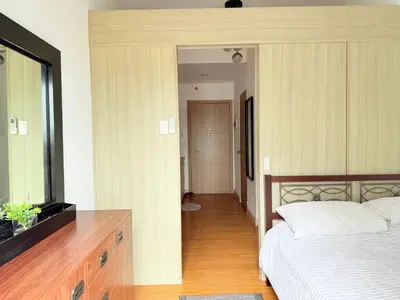a bedroom with a bed and a dresser with a television at Sunshine at Grace nr BGC in Manila