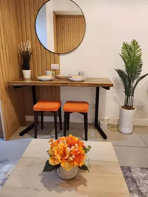 a table with orange chairs and a vase of flowers at 331D Near MOA and Airport Pool View Fast WiFi Balcony in Manila