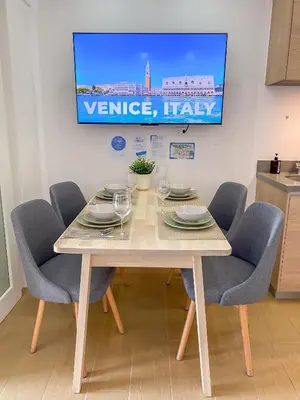a dining room table with chairs and a tv on the wall at nJoy! CHIC & Luxury at Venice Grand Canal in Manila