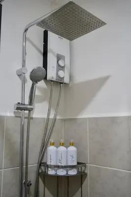 a shower with four shampoo bottles on a shelf in a bathroom at NUVALI Amaia Steps Parkway 2 BR Condo THE SANCTUARY with pool, free parking near Carmelray Industrial Park, Ayala Solenad, Xavier School in Pitland