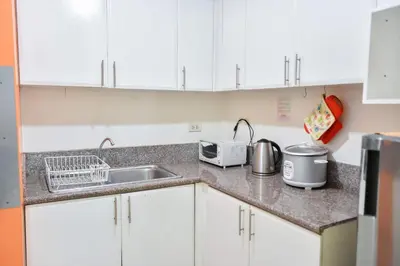 a kitchen with white cabinets and a sink at Lovely Modern 2BR Condo in Aurora Gardens San Juan City in Manila