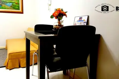 a desk with two chairs and a table with a vase of flowers at 1BR Solemare Aseana MOA Okada Ayala Bay Mall COD Paranaque w/WIFI in Manila