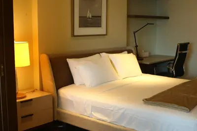 a bedroom with a bed with a lamp and a desk at Poblacion Penthouse Suite with Private Roofdeck in Manila