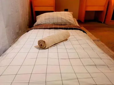 a bed with a towel laying on the floor at HomeBase Apartment Hotel in Manila