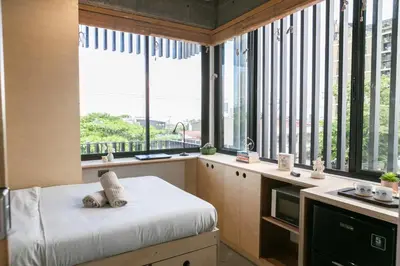 a bedroom with large windows and a bed with pillows at HomeBase Apartment Hotel in Manila
