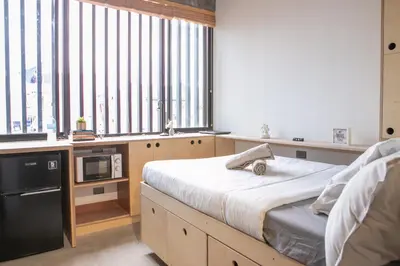 a bedroom with a bed and a microwave and windows at HomeBase Apartment Hotel in Manila