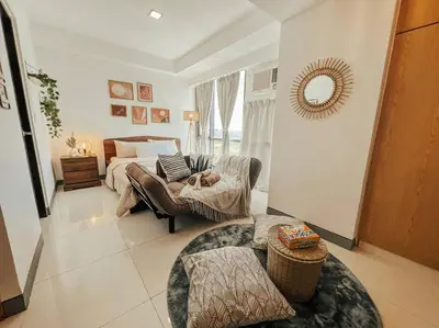 a living room with a dog sleeping on a couch at Chic and Cozy Studio Viceroy Residences Taguig in Manila