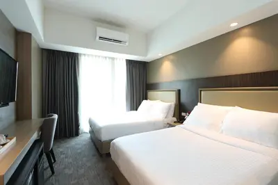 a hotel room with two beds and a window at Sotogrande Hotel Katipunan in Manila