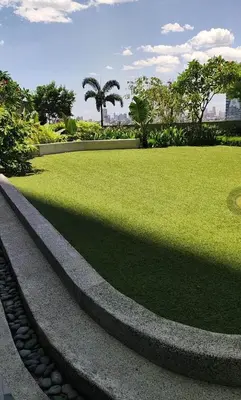 a park with a grassy field and palm trees at Air Residences 1-Bedroom condo in Makati in Manila