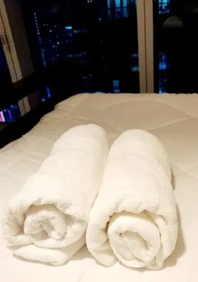 two rolls of white towels sitting on a bed at Casa Antonio At Uptown Parksuites Two in Manila