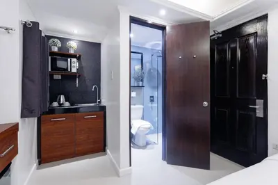 a bathroom with a sink and a toilet and a door at Nest Nano Suites Poblacion - Makati in Manila
