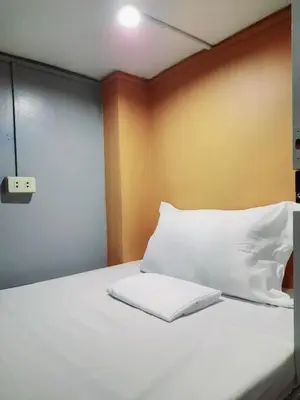 a bed with white sheets and pillows in a room at Budget Transient Capsule Room Makati near Ayala and Buendia in Manila