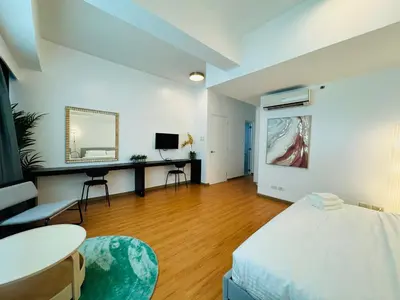a bedroom with a bed and a table and a mirror at Avant at the Fort by Urban Realty in Manila