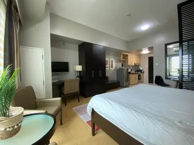 a bedroom with a large bed and a kitchen at Avant at the Fort by Urban Realty in Manila