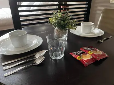 a black table with two plates and cups and silverware at Avant at the Fort by Urban Realty in Manila