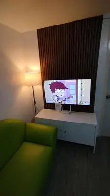 a living room with a green couch and a flat screen tv at ADB Avenue Tower Ortigas Manila in Manila