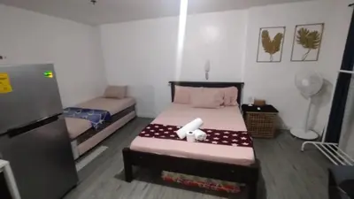 a small room with two beds and a refrigerator at ADB Avenue Tower Ortigas Manila in Manila