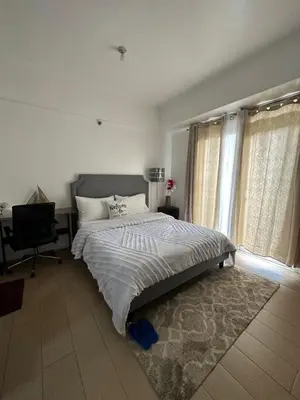 a bedroom with a bed and a chair and a window at Cecillian place staycation @ pasay in Manila