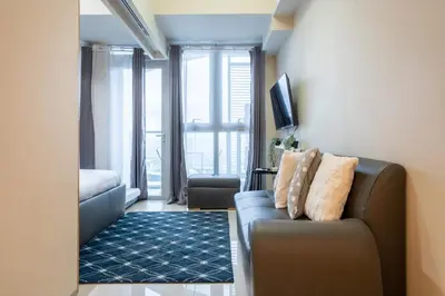 a living room with a couch and a large window at Uptown Parksuites BGC 1BR, Hi Flr Great view fr Balcony with Washer in Manila