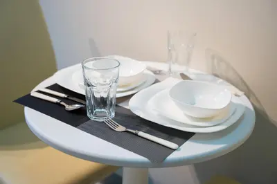 a white table with plates and glasses on it at Uptown Parksuites BGC 1BR, Hi Flr Great view fr Balcony with Washer in Manila