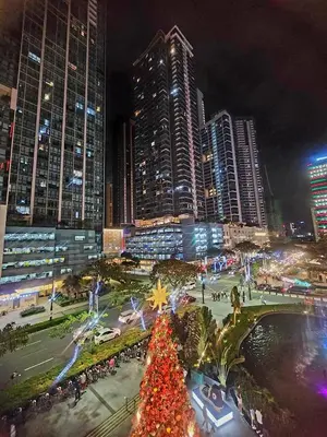 a christmas tree in the middle of a city at night at 20F Modern Cozy BGC Suite across 2 Major Malls with Washer FREE Parking in Manila