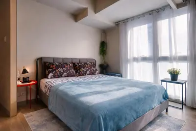 a bedroom with a bed and a large window at 20F Modern Cozy BGC Suite across 2 Major Malls with Washer FREE Parking in Manila