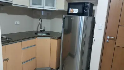 a kitchen with a refrigerator with a microwave on top of it at Hilanders Condotel in front of Terminal 3 in Manila