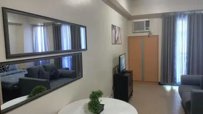 a living room with a mirror and a couch at Hilanders Condotel in front of Terminal 3 in Manila