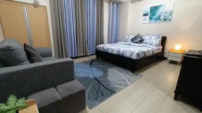 a living room with a couch and a bed in it at Hilanders Condotel in front of Terminal 3 in Manila