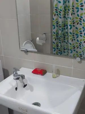 a white bathroom sink with a mirror and a shower curtain at MOA staycation by Elsie D in Manila