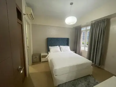 a bedroom with a bed with a blue headboard and a window at 150 Newport Blvd - Near T3 Airport in Manila