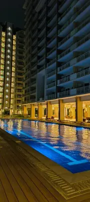 an empty swimming pool at night with tall buildings at Condo for Families and Friends in Manila