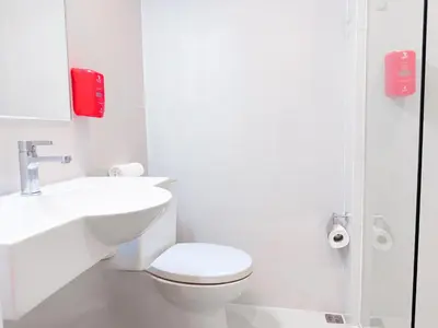 a white bathroom with a toilet and a sink at Red Planet Manila Aseana City in Manila