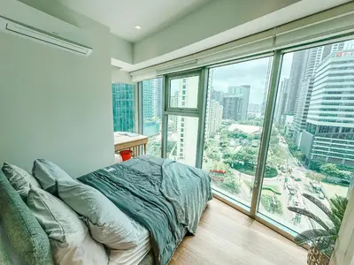 a bedroom with a bed and a large window at Vibrant Oasis with the best view + Fast WiFi in Manila