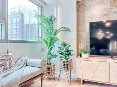 a living room with two potted plants and a tv at Vibrant Oasis with the best view + Fast WiFi in Manila