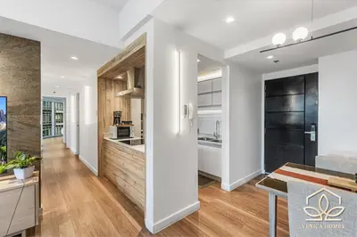 an open kitchen and living room with white walls and wood floors at Vibrant Oasis with the best view + Fast WiFi in Manila