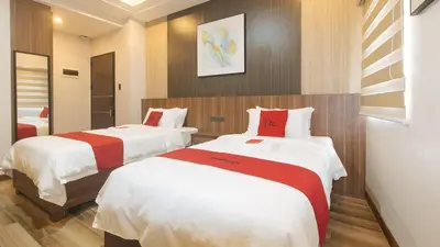a bedroom with two beds with white and red sheets at RedDoorz Plus @ Bez Tower and Residences San Juan in Manila
