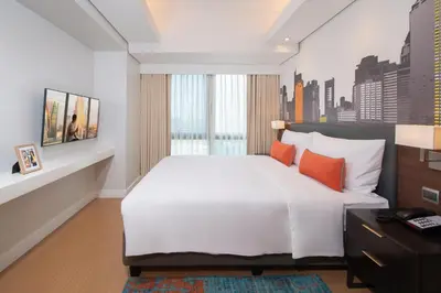 a bedroom with a large white bed with orange pillows at Citadines Benavidez Makati in Manila
