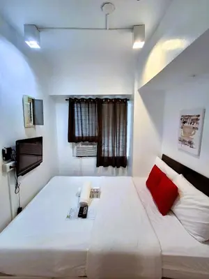 a bedroom with a large white bed with a red pillow at Makati Poblacion Hotel in Manila