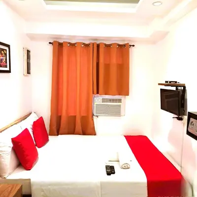 a bedroom with a bed with red pillows and a window at Makati Poblacion Hotel in Manila